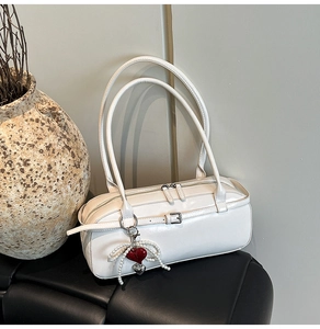 Close-up of white leather pillow bag with pearl heart charm and dual zipper detail