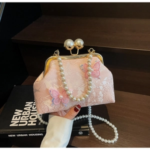 Détail du sac en jacquard rose avec broderie papillon et fermoir à perles chic
