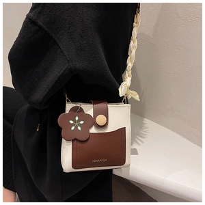Detail of a mini two-tone crossbody bag with flower charm and gathered strap on model
