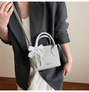 Detail of grey lychee leather bucket bag with pearl pendant and silk bow decoration