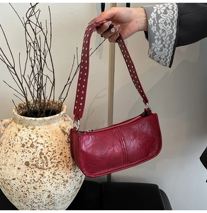 Close-up of silver rivet studs on vintage dark red shoulder bag with faux leather texture