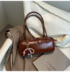 Detailed macro view of dark brown faux leather pillow bag with pearl bow and heart charm