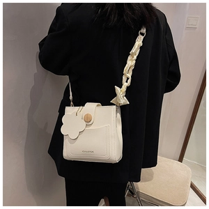 Close-up of cream square crossbody bag with floral charm and silk scarf handle detail