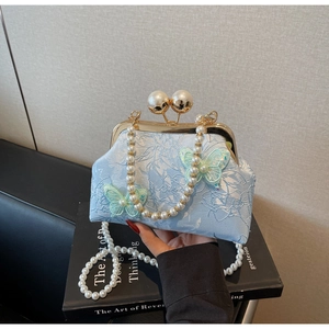 Détail du sac de soirée en jacquard bleu clair avec broderie papillon 3D et fermoir perle