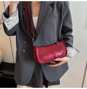 Close-up of retro red crossbody bag with vertical stitching and silver metal hardware