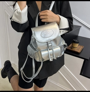 Silver metallic leather backpack shown on a model with drawstring closure and multi-pockets