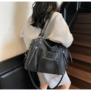 Detail view of large black tote bag featuring pebbled leather and multiple zipper pockets