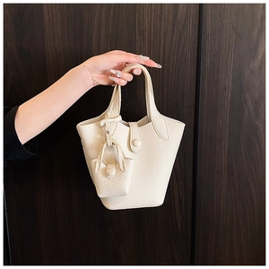 Close-up of beige lychee grain leather bucket bag with a matching mini pouch charm