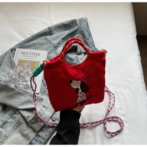 Detailed close-up of red canvas bag with cartoon dog embroidery and woven strap