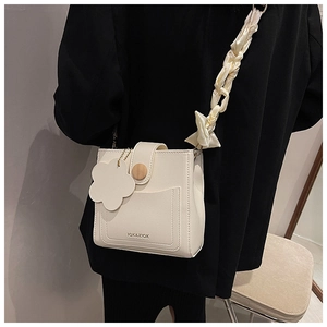 Detail view of cream square crossbody bag with silk scarf strap and flower pendant