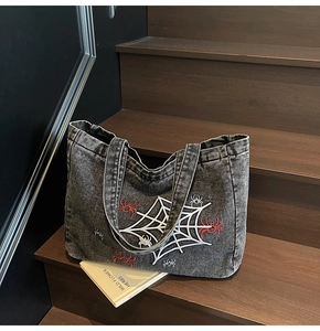 Detail showing high-quality embroidery of spider web and spider on washed denim tote bag