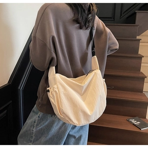 Detail view of large cream canvas crescent bag with adjustable drawstring and wide strap