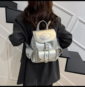 Detailed view of metallic silver backpack with functional flap pockets and metal buckle