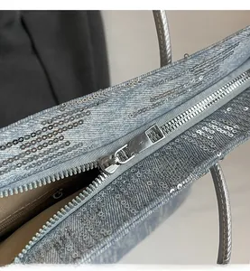 Detail shot of the smooth metal zipper and silver sequined fabric on the tote bag