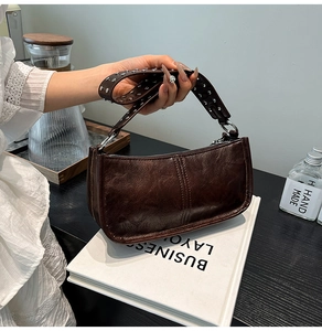 Detail of vintage brown oil wax leather bag with silver studs on the wide shoulder strap