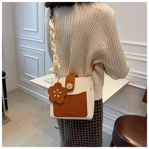 Detail of vintage cream crossbody bag with brown pocket, wooden button and floral charm