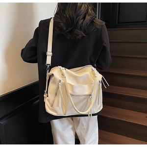 Detail of white litchi pattern leather tote bag with stylish zipper tassels and strap