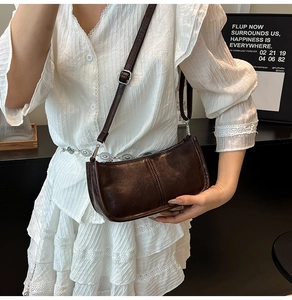 Detail of dark coffee rivet crossbody bag with adjustable silver buckle on model