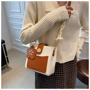 Detail of color-block mini square bag with floral charm and silk-wrapped strap