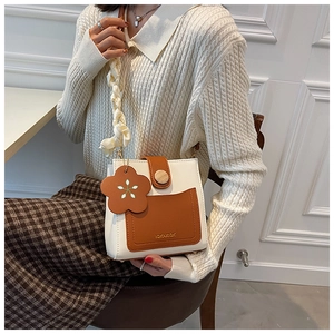 Detail of color-block mini square bag with woven scarf strap and leather flower charm