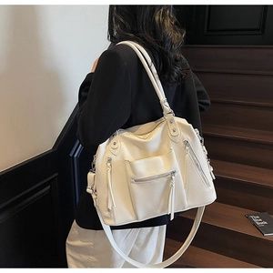 Detailed view of cream leather tote bag with fringe zippers shown on stairs
