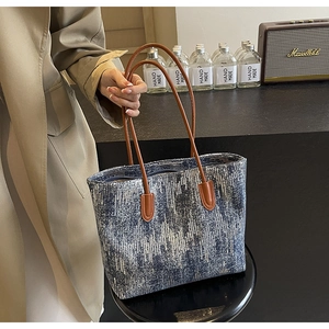 Detail of blue sequin tote bag with brown leather handles and secure zipper closure