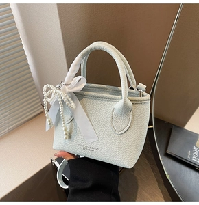Detail of light blue lychee pattern leather bucket bag with pearl bow and silk ribbon