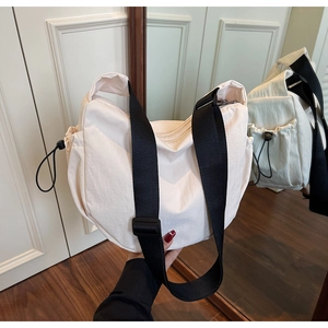 Detail of canvas crescent bag with wide black strap and drawstring side pocket in macro view