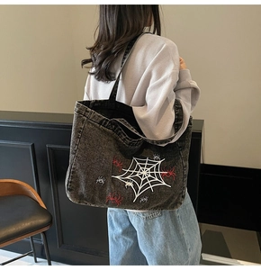 Macro view of detailed spider web embroidery on vintage washed denim shoulder bag
