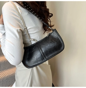 Detail of black faux leather shoulder bag featuring stylish silver metal rivets on strap