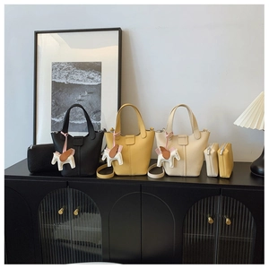 Three lychee grain leather bucket bags in black, yellow, and beige with horse charms