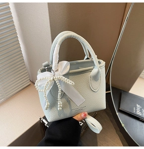 Detail of light blue lychee texture handbag with pearl bow and ribbon-wrapped handle