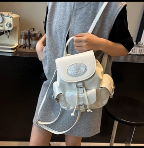 Detail of white glossy leather backpack with flap closure and decorative front pocket