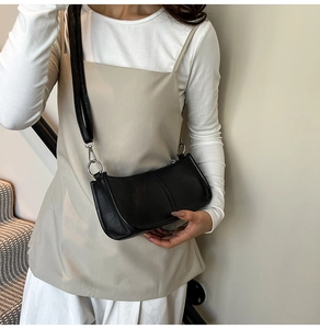 Detail shot of a black leather rivet shoulder bag showing textures and silver rings