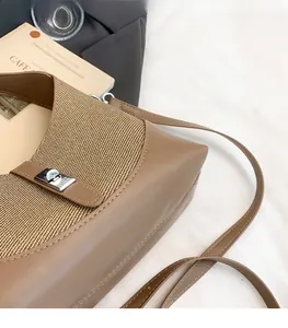 Detail of contrasting brown woven shoulder bag with silver turn-lock clasp and leather strap