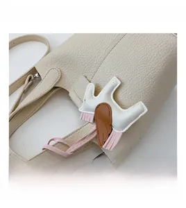 Close-up of cream lychee leather bucket bag with a decorative horse leather charm