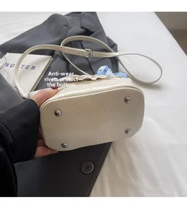 Détail des rivets anti-usure sur le fond d'un sac seau plissé de couleur crème