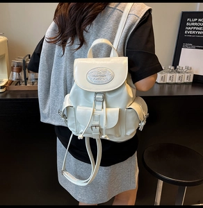 Detailed view of the white glossy water-resistant backpack with buckle and drawstring