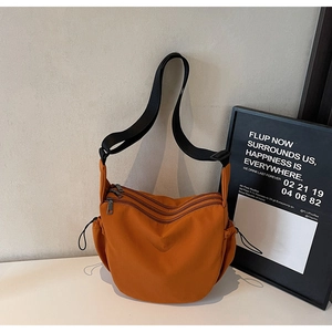 Detail view of orange canvas crossbody bag with multi-zipper layers and drawstring pockets