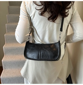 Detail of a vintage black crescent shoulder bag featuring matte leather texture and silver buckle