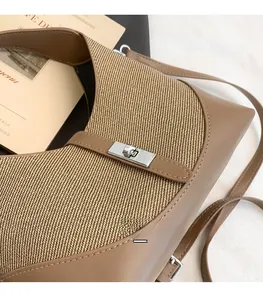 Close-up of contrast stitching and silver metal swivel lock on high-quality crossbody bag