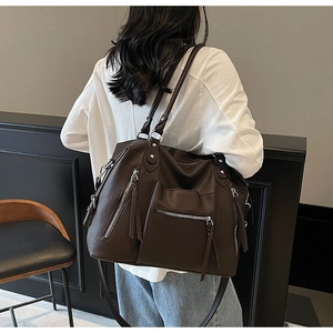 Close-up of large brown leather tote bag with functional zippers and multiple strap options