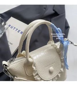 Détail du sac seau plissé crème avec bordure en dentelle et ruban à carreaux bleus