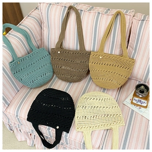 Detail view of five multi-colored hollow crochet tote bags with golden metal pendants
