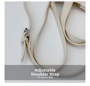 Detail view of adjustable beige leather shoulder strap with silver metal buckle on bucket bag
