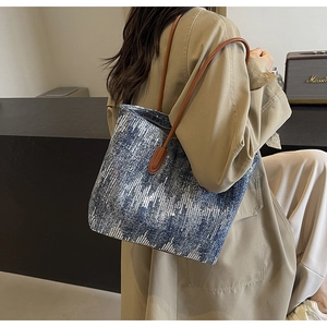 Fashionable denim blue sequin tote bag with brown leather straps shown on a model
