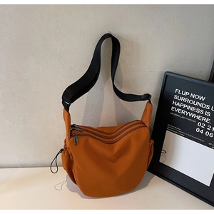Close-up of caramel crescent canvas bag showing three functional zippers and texture