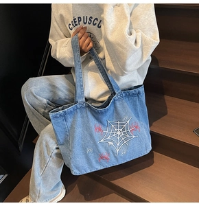 Detail of vintage denim tote bag featuring white spider web and red spider embroidery