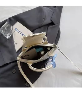 Vue détaillée d'un sac crème montrant l'espace intérieur pour téléphone et maquillage