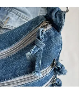 Detail of silver metal zippers with denim pullers on a vintage blue denim tote bag